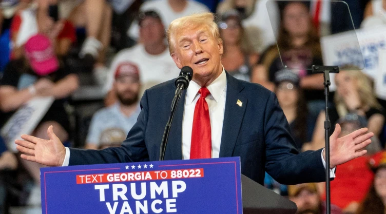 Donald Trump brindando un discurso, parado frente al micrófono con el público presente