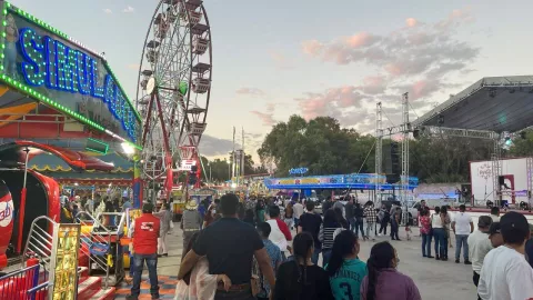 personas caminando entre juegos mecánicos