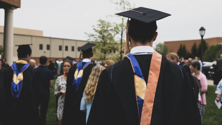 Un estudiante en su gradación de la universidad con la toga, la esclavina, el birrete y la borla