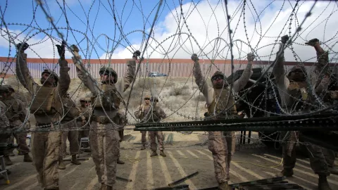 Los marines estadounidenses ajustan el alambre de concertina a lo largo de la valla principal en la frontera entre México y Estados Unidos.