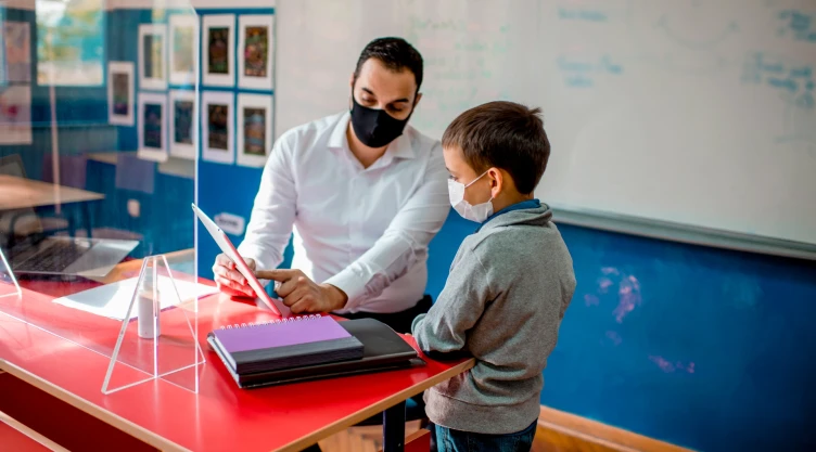 Un docente y un alumno de primaria con mascarillas.