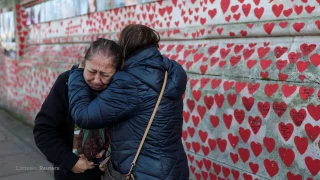 reino_unido_dia_de_reflexion_conmemorar_cinco_anos_pandemia_covid_19_memorial_personas_abrazadas_muro_corazones_rojos