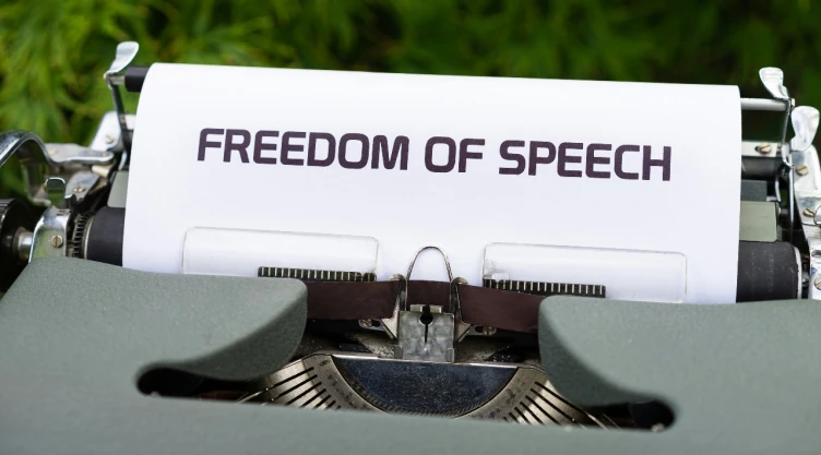 Foto de máquina de escribir con una hoja de papel con la frase “freedom of speech”.
