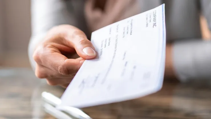 Una persona entrega un cheque a otra.