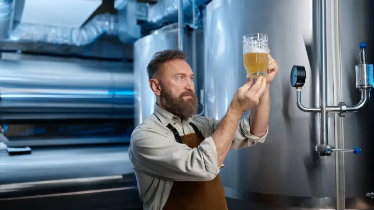 un hombre en una fábrica de cervezas analiza la malta y su consistencia