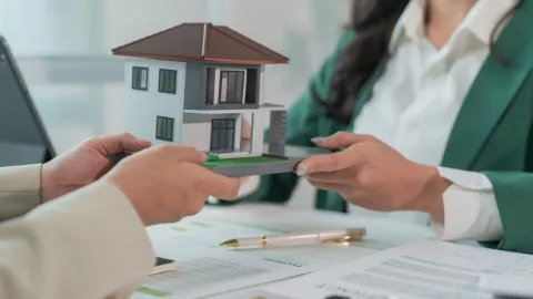 Una mujer entrega una casa modelo a otra persona.