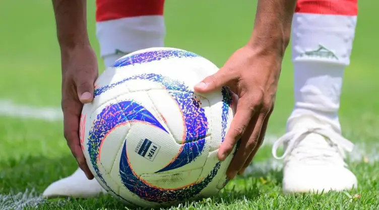 Jugador de la Liga MX agarrango el balón para tirar un penal