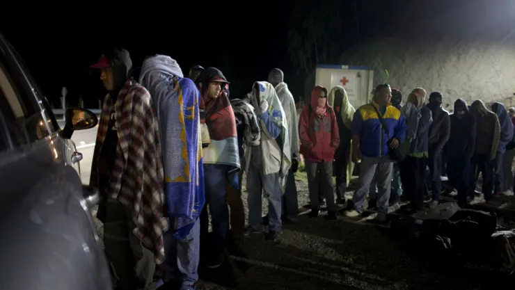 Migrantes venzolanos hacen fila para recibir pan y café que reparte una familia colombiana desde su auto, en una gasolinera en Pamplona, Colombia. Imagen, AP.