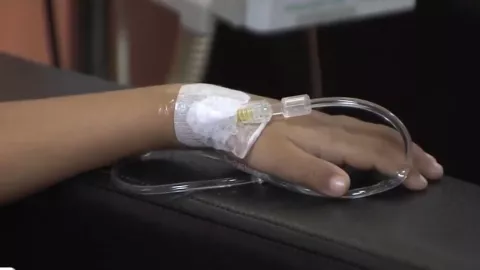 Mano de menor recibiendo medicamentos contra el cáncer.