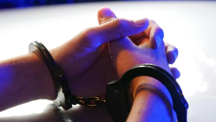 Manos entrelazadas con esposas en las muñecas