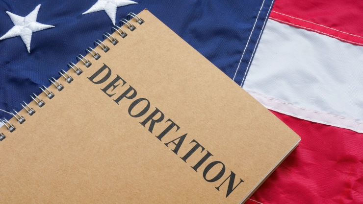 Una libreta con el nombre deportación sobre una bandera estadounidense.