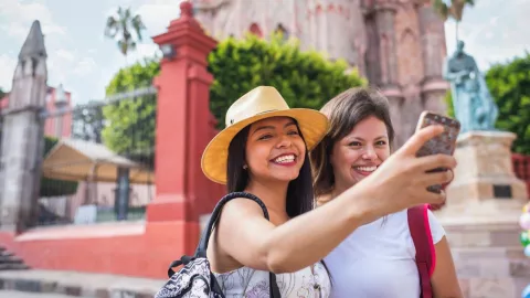 Dos mujeres jóvenes tomándose una selfie fuera de la catedral de San Miguel Allende en Guanajuato