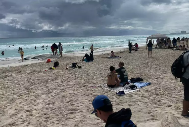 Turistas disfrutan de la playa de Cancun a pesar del cielo nublado