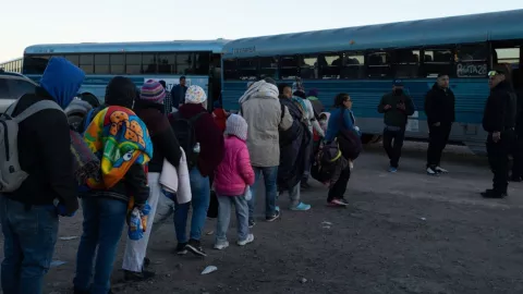Un grupo de migrantes hace una fila para subir a unos buses que los llevarán a otros estados de Estados Unidos.