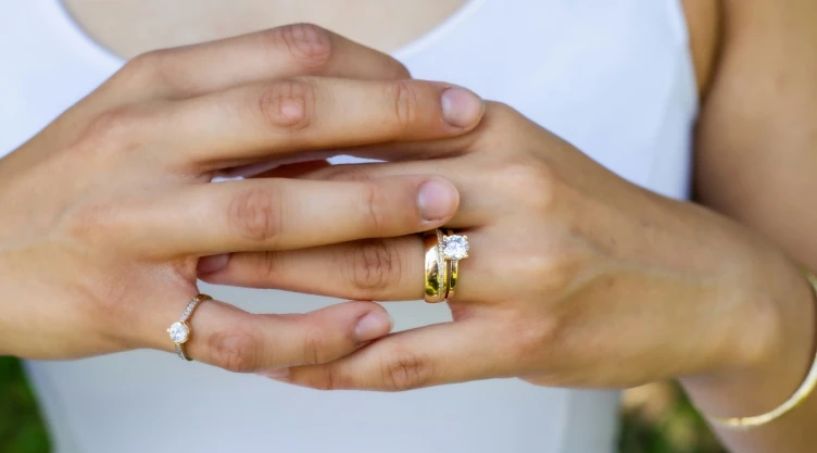 Primer plano de manos de mujer mostrando un anillo de compromiso.