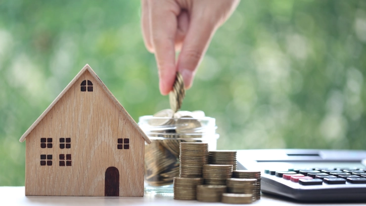 Una maqueta de vivienda y dinero alrededor.