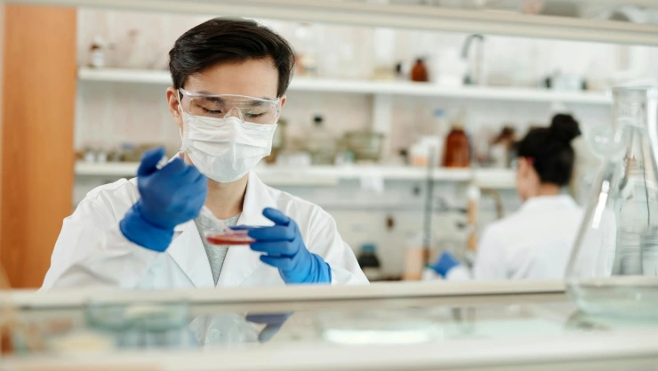 Laboratorista con guantes y cubrebocas analizando alguna muestra