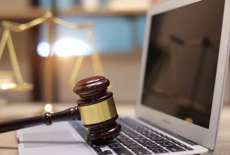 computadora con un mazo de juez y de fondo una balanza