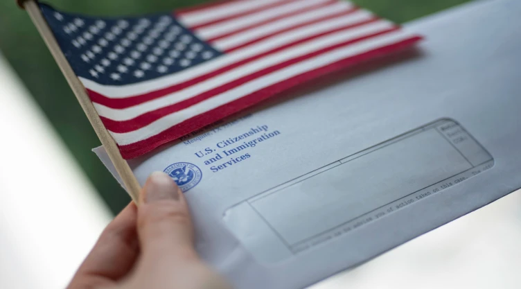 Una carta del USCIS y una bandera estadounidense.