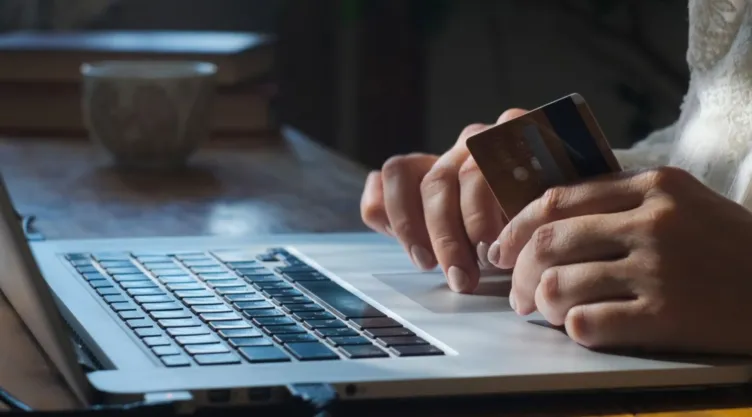 Una persona está frente a una computadora con una tarjeta bancaria.