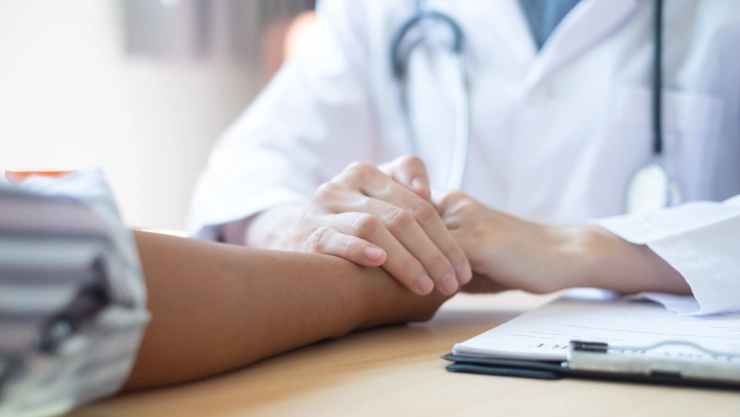 Un profesional de la salud agarra de la mano a un paciente.