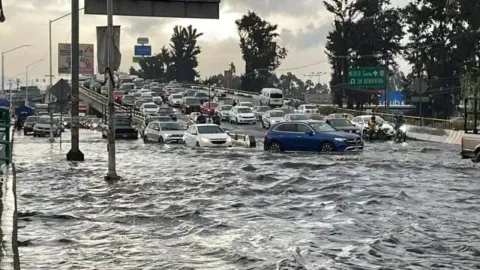 Inundaciones en la CDMX, coches se orillan para evitar pasar sobre un espejo de agua.