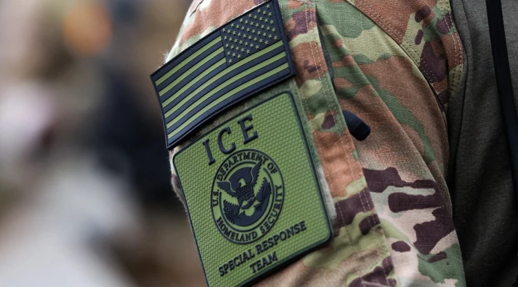 Toma cerrada de logotipo de ICE de EU en uniforme de agente migratorio.