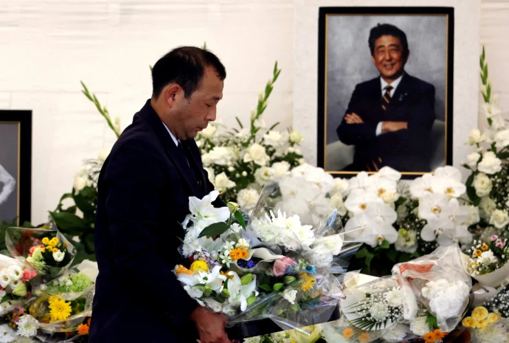 Fotografías de retratos del difunto primer ministro japonés Shinzo Abe , quien recibió un disparo mientras hacía campaña para las elecciones parlamentarias de 2022, se colocan en un altar mientras las flores ofrecidas por los dolientes se retiran del altar durante la ceremonia de conmemoración de un año de su asesinato en el templo Zojoji en Tokio, Japón, el 8 de julio de 2023.