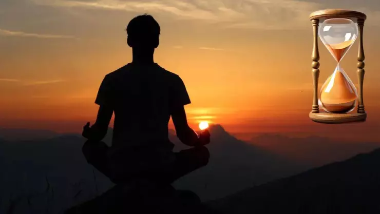 Persona meditando. Una puesta de sol de fondo y un reloj de arena