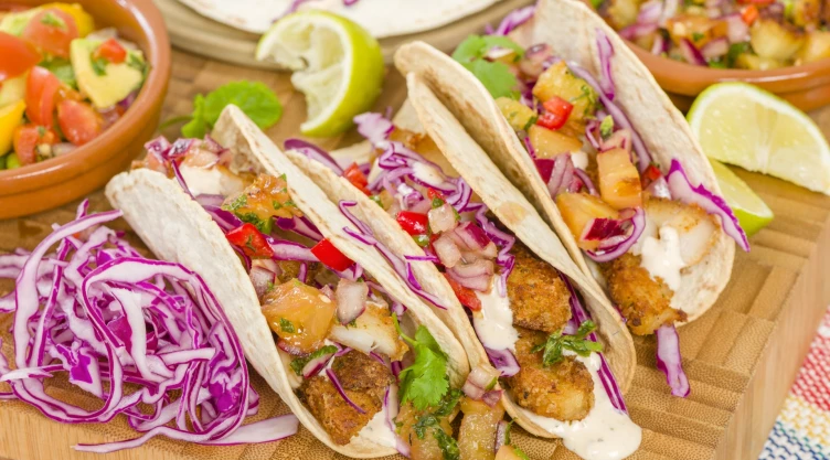Tres tacos servidos en la mesa con sus respectivos ingredientes, listos para comer