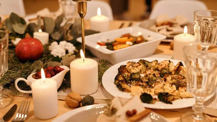 Cena navideña: platos, copas de cristal, velas encendidas. 