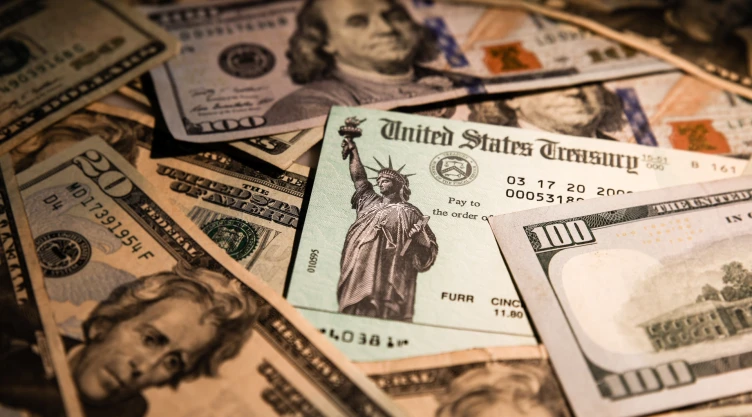 una imagen con dólares de por medio y un cheque