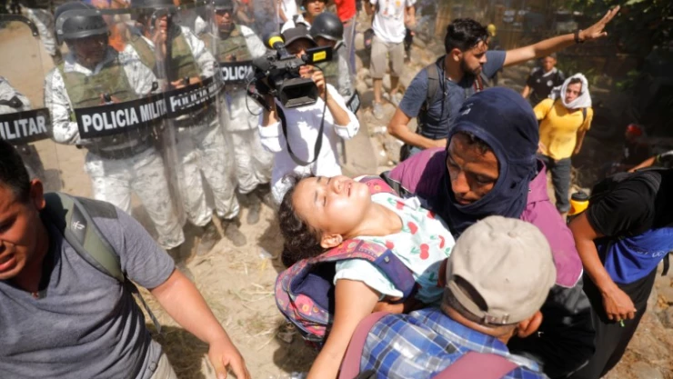 Foto del lunes de migrantes en viaje a EEUU llevando a una niña cerca de la frontera entre Guatemala y México