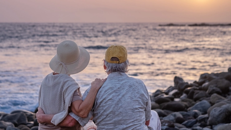 una pareja de jubilados feliz y contemplando el atardecer sobre la playa