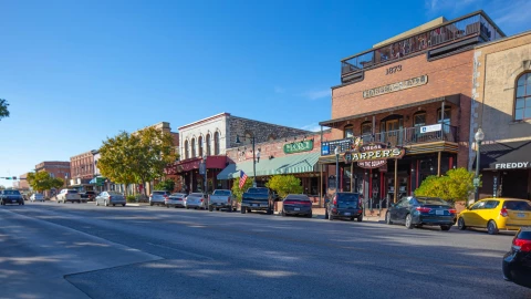 Una de las calles principales de San Marcos, Texas, con autos estacionados en los locales y las casas bajitas.