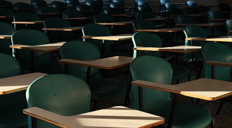 Salón de clases vacío: butacas verdes son iluminadas por el sol.