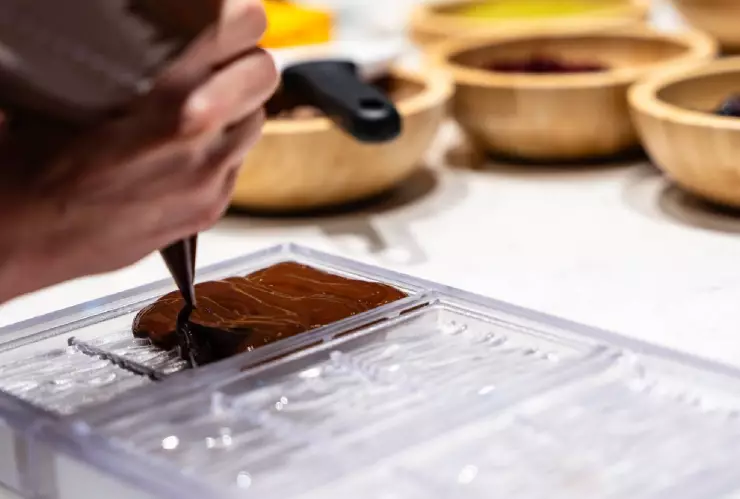 un chef vierte el chocolate de una manera muy cuidadosa