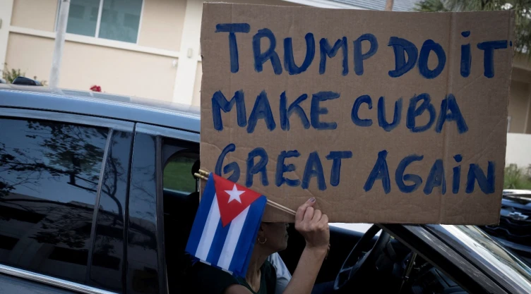 Una mujer sostiene un cartel y banderas cubanas mientras partidarios del presidente estadounidense Donald Trump participan en una protesta contra el gobierno de Cuba , en Miami, Florida, EE. UU., el 28 de febrero de 2026.
