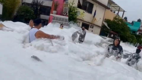 Vecinos juegan con la espuma provocada por el desbordamiento de la presa.