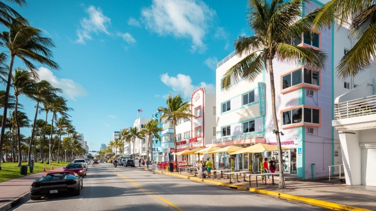 La avenida costera de Miami Becha con sus típicas palmeras, autos de lujo estacionados y los bares en frente