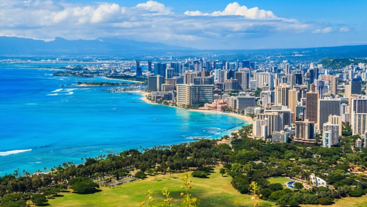 Vista aérea de la ciudad de Honolulu, donde se ve la playa de aguas turquesas, la vegetación y los edificios