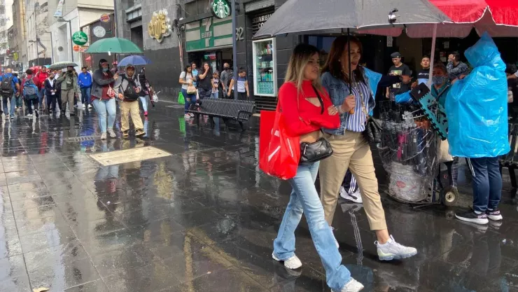 personas se resguardan de la llovizna con paraguas