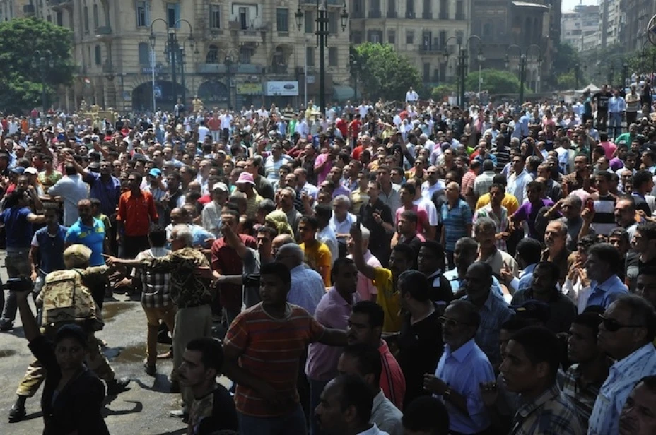 Un miembro de las fuerzas de seguridad de Egipto (a la izq.) intenta mantener a una turba enfurecida lejos de la mezquita de al Fatá