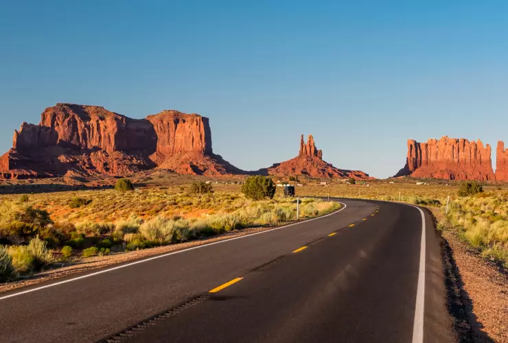 Una carretera desierta en Arizona con el fondo de montañas rocosas de color rojizo