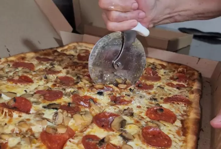 Una pizza recién hecha siendo cortada