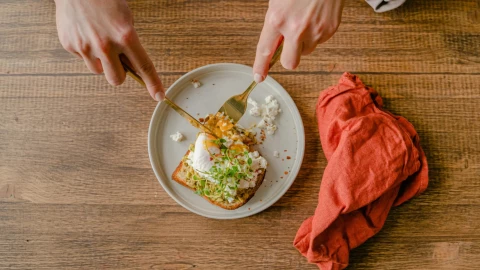 Una persona comiendo un pan con huevo y berro