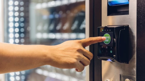 Una mano pulsa su selección en una máquina expendedora
