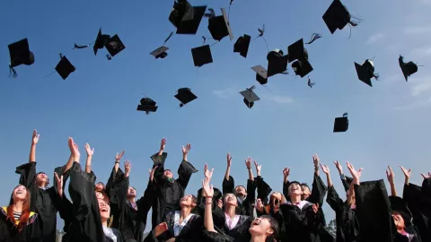 Estudiantes lanzando su sombrero de graduación