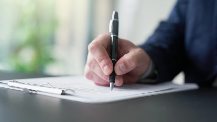 Una persona firma un documento.