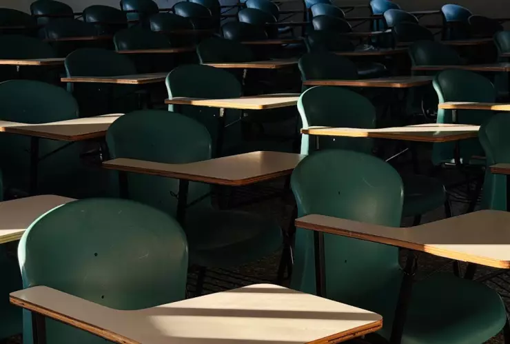 Salón de clases vacío: butacas verdes son iluminadas por el sol.